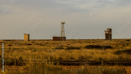 Sunrise over a single beach: Fishing boats rest on the shingle beach, bathed in the warm glow of the morning light, as the serene coastal landscape awakens