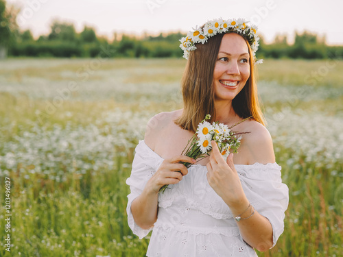 beautiful girl walks in a flower field at sunset in the summer of the country photo