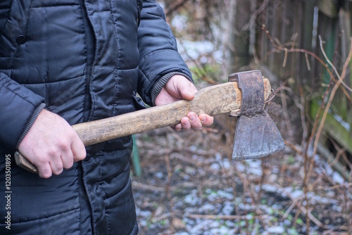 hands of one male worker holding big old grey axe on winter street photo