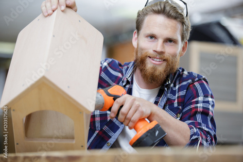 young happy man is drilling a small house photo