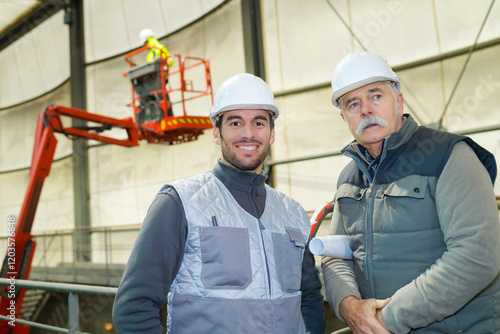 portraot of two workmen with cherry picker active in background photo