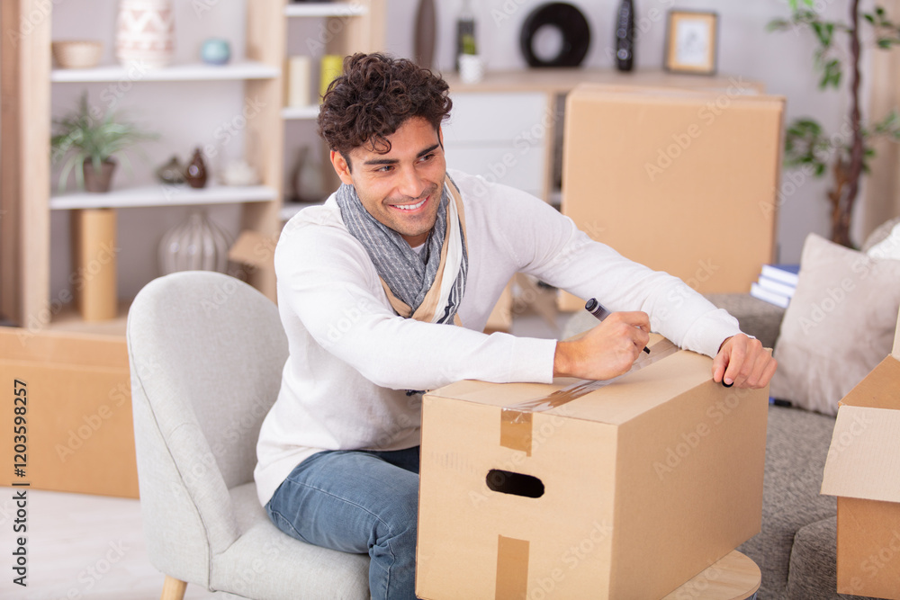 young man unpacking at new house with boxes young man unpacking at new house with boxes