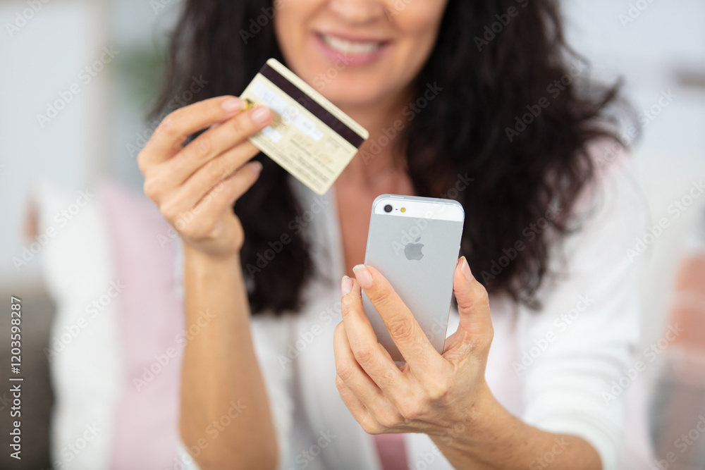 woman holding credit card in one hand and telephone