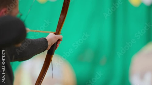A man is holding a bow and arrow and is about to shoot it. Concept of focus and determination as the man prepares to take his shot