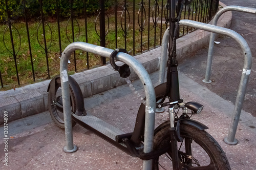 Electric scooter locked securely to metal railing, demonstrating urban parking safety and responsible micromobility infrastructure