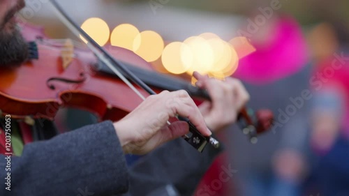 A man is playing a violin in front of a crowd. The crowd is watching him intently