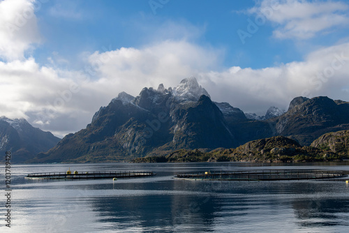 Some salmon pens for farming in Raftsundet waters near Hadsel, Norway and entrance toTrollfjord (Trollfjorden) with mountains covered in first dusting of snow on Lofoten island chain archipelago photo