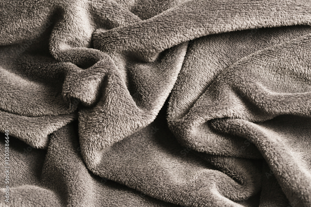 Fototapeta premium Soft, crumpled grey blanket with wavy texture. Closeup of plush, wrinkled fabric with shadows. Cozy cotton textile background.