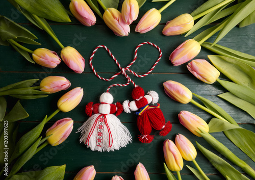 Martenitsa, Martisor, on a green wooden table framed with pink tulips