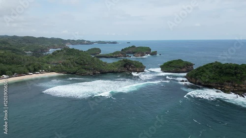 Aerial footage of a hidden paradise in the world that is very beautiful, small waves, lush green trees and cloudy sky