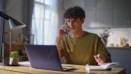 Confident freelancer speaking smartphone home office closeup. Curly man calling photo