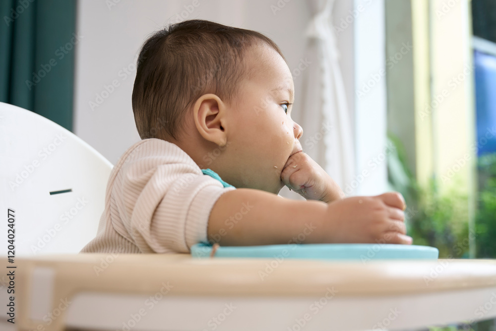 The baby is eating and looking outside The baby is eating and looking outside