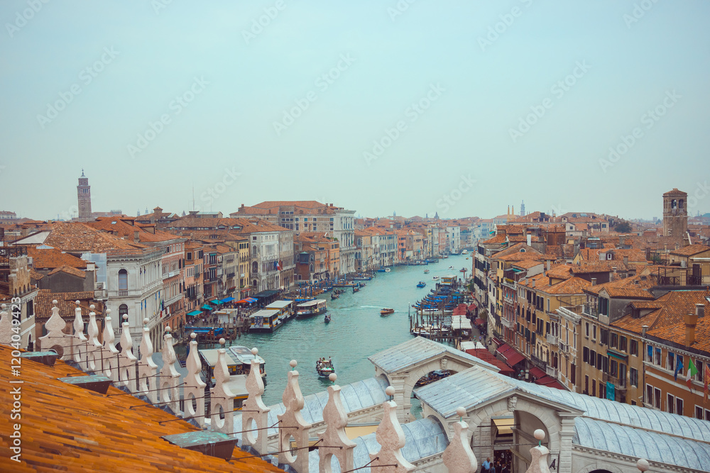 Obraz premium A stunning aerial view of the Grand Canal in Venice, Italy, surrounded by historic buildings, vibrant terracotta rooftops, and bustling waterways. Perfect for travel and cultural imagery.