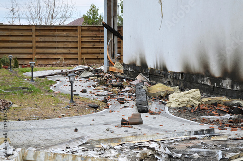 Aftermath of a devastating fire that destroyed a private home. Ruins of the house after the fire, debris from construction materials and rubbish scattered in the courtyard.