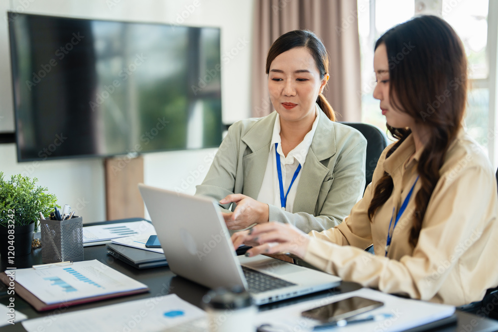Female senior and junior managers sitting at desk working together in a business team Female senior and junior managers sitting at desk working together in a business team