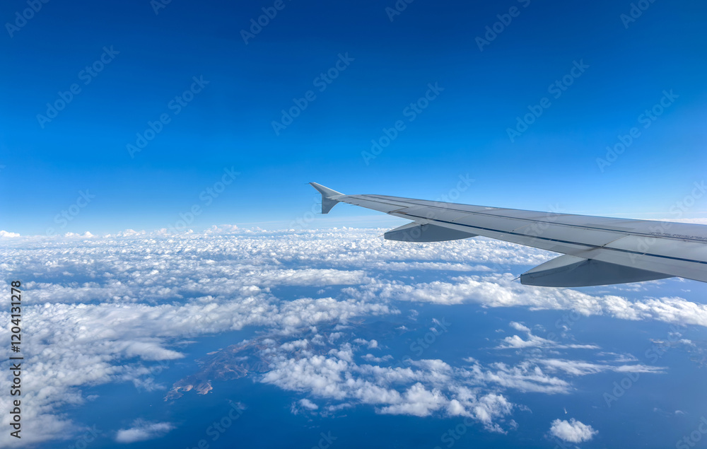 Plane flying over clouds, view from airplane window, fluffy cloudscape and blue sky