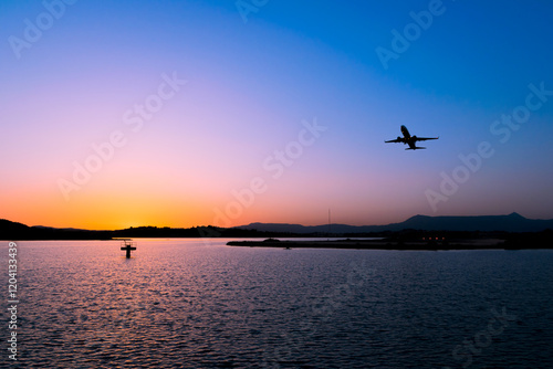 Plane take off with sunset sky and Halikiopoulou Lagoon bellow on Corfu island, Greece