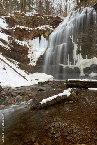 A long exposure blurred motion gorgeous cascading waterfall in the late winter, early spring, with melting snow and ice.