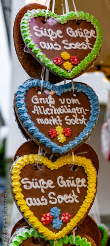 Three colorful heart-shaped cookies with different words written on them.Soest Allerheiligenkirmes