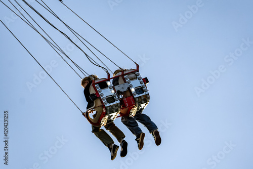 Two people are swinging on a ride, one of them is wearing a black shirt photo