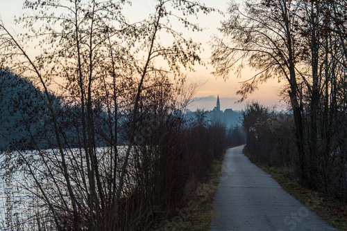 Radweg an der Traun in Wels mit Blick auf die Pfarrkirche in Thalheim bei Sonnenuntergang photo