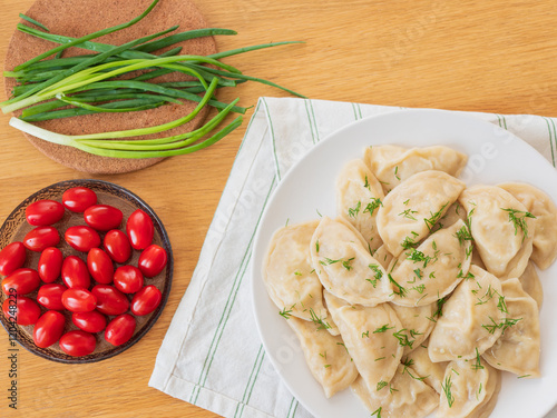 Vegan dumplings gyoza with dill and green onions, cherry tomatoes on wooden table