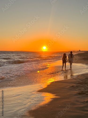 Two people walking on a beach at sunset in vale do lobo portugal