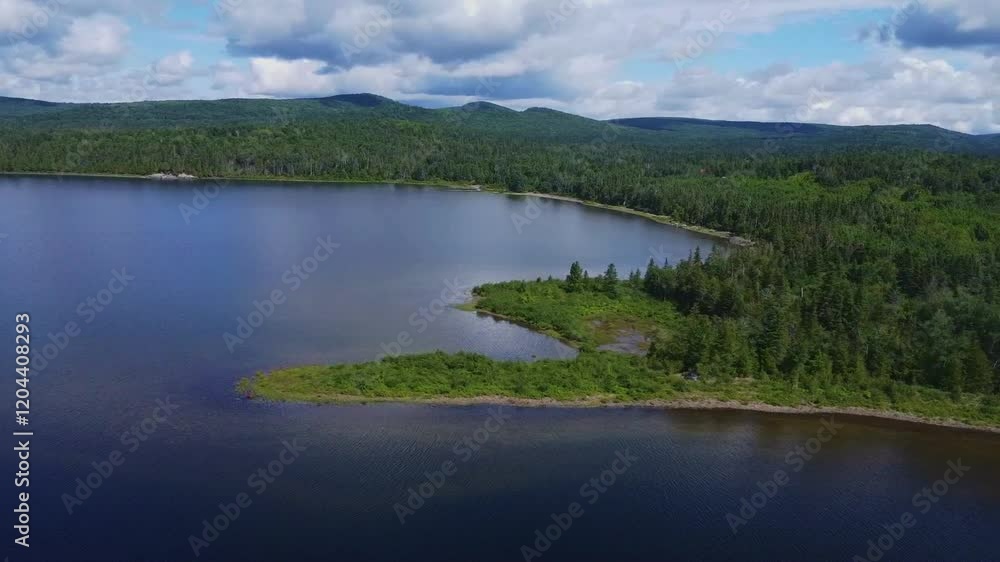 Panoramic aerial view of the immense Lake Matapedia surrounded by lush and green forest as far as the eye can see under a cloudy sky. Panoramic aerial view of the immense Lake Matapedia surrounded by lush and green forest as far as the eye can see under a cloudy sky.