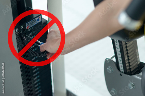 Adjusting gym equipment weight with red prohibition sign symbolizing safety precautions or improper usage warning photo