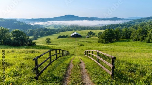 Serene morning mist over valley farm,  dirt road leads to barn; idyllic rural landscape, perfect for travel brochures