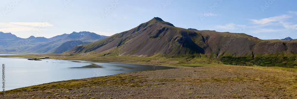 Mountain fjord landscape in Iceland with coastal terrain. Dramatic cliffs meet calm waters under summer sky Mountain fjord landscape in Iceland with coastal terrain. Dramatic cliffs meet calm waters under summer sky