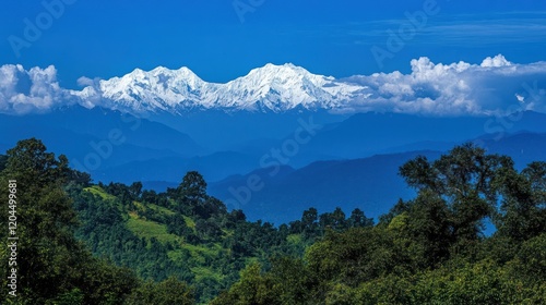 Panoramic view of snow-capped mountains rising above lush green hills under a vibrant blue sky with fluffy clouds.