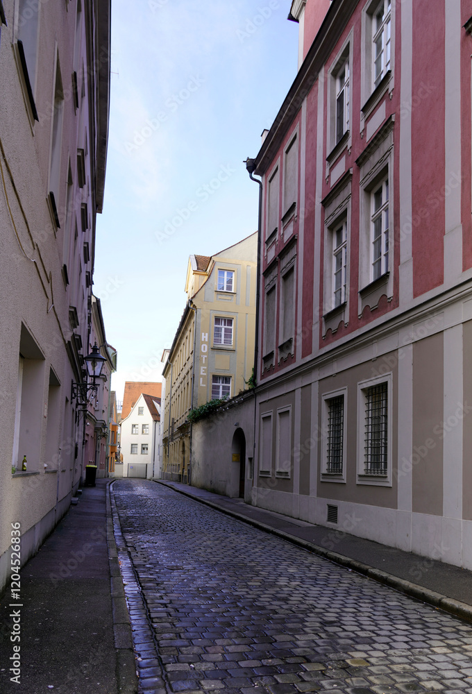 Fototapeta premium Narrow cobblestone street lined by tall houses on either side in a medieval town in southern Germany