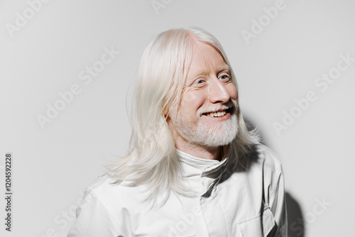 Smiling elderly man with long white hair and beard against a plain light background, showcasing a serene expression and contemporary attire, ideal for health and wellness themes photo