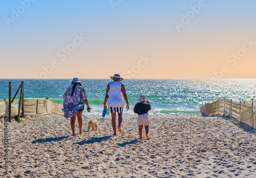 An African family enjoys a sunset stroll to the beach with their child and dog at Sunset Beach, Cape Town, South Africa