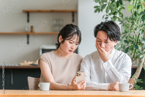 Konstfotografi 家でスマートフォンを見ながら落ち込む夫婦・カップル（驚く・ニュース・投資・株）