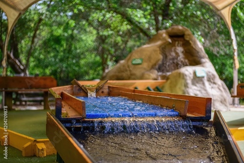 Canvas Print Mining sluice boxes in a shady grove, water rushing over rocks, re-creating gold panning experience in a lush setting