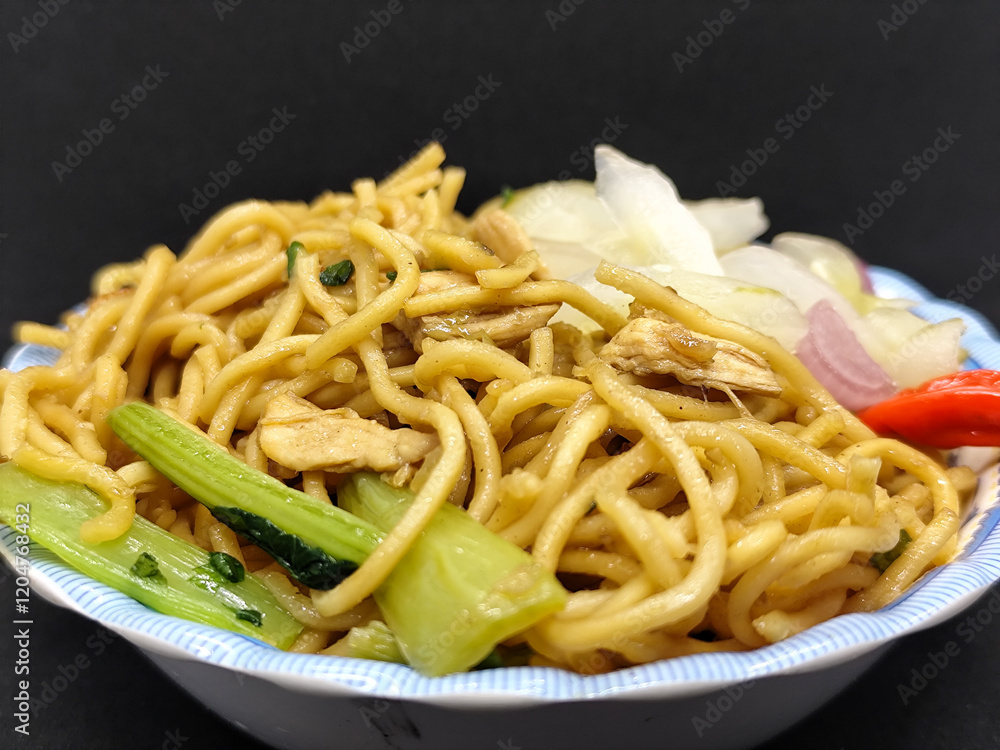 Fried noodles with soy sauce served with pickles, chili, vegetables and meat. Fried noodles with black background. Fried noodles with soy sauce served with pickles, chili, vegetables and meat. Fried noodles with black background.
