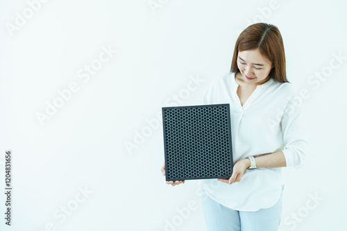 Asian woman showing the new carbon air purifier filter to camera close up. HEPA filter used in high efficiency air purifier system to purify the dirty or polluted air inside the house or vehicle. photo