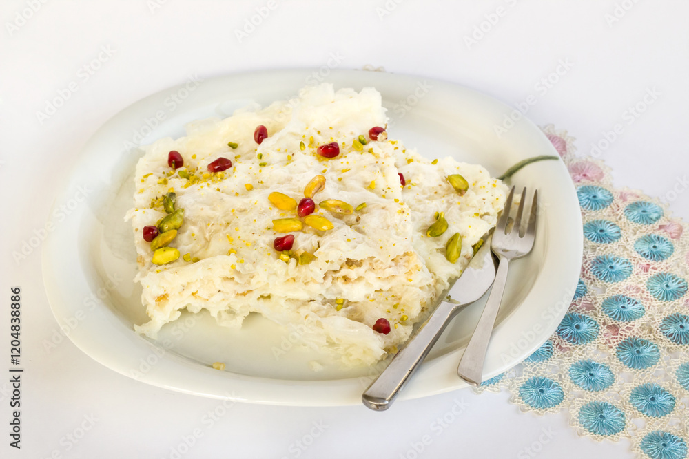 Traditional,Turkish Ramadan Dessert Gullac one portion on plate with cutlery and blue lace Traditional,Turkish Ramadan Dessert Gullac one portion on plate with cutlery and blue lace