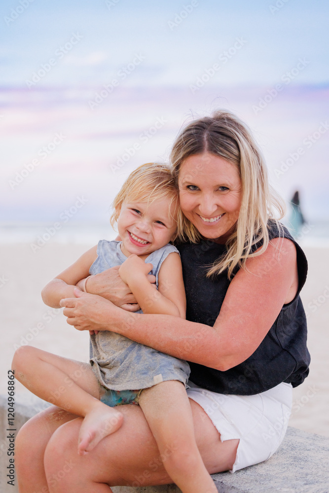 Mother and child embracing on the beach with pretty pink and purple sunset sky Mother and child embracing on the beach with pretty pink and purple sunset sky