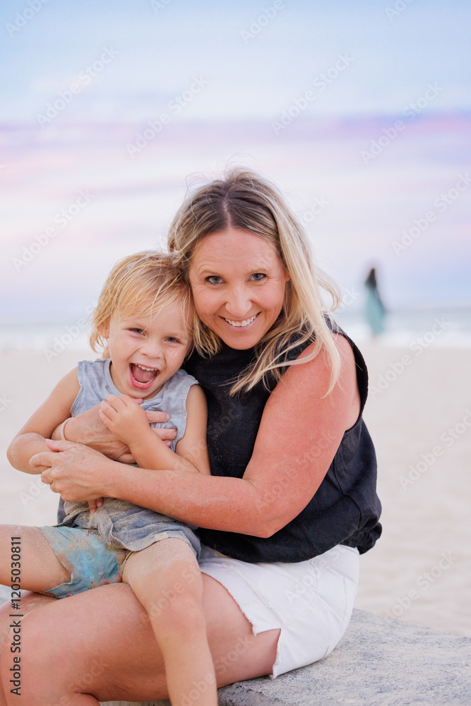 Mother and child embracing on the beach with pretty pink and purple sunset sky Mother and child embracing on the beach with pretty pink and purple sunset sky