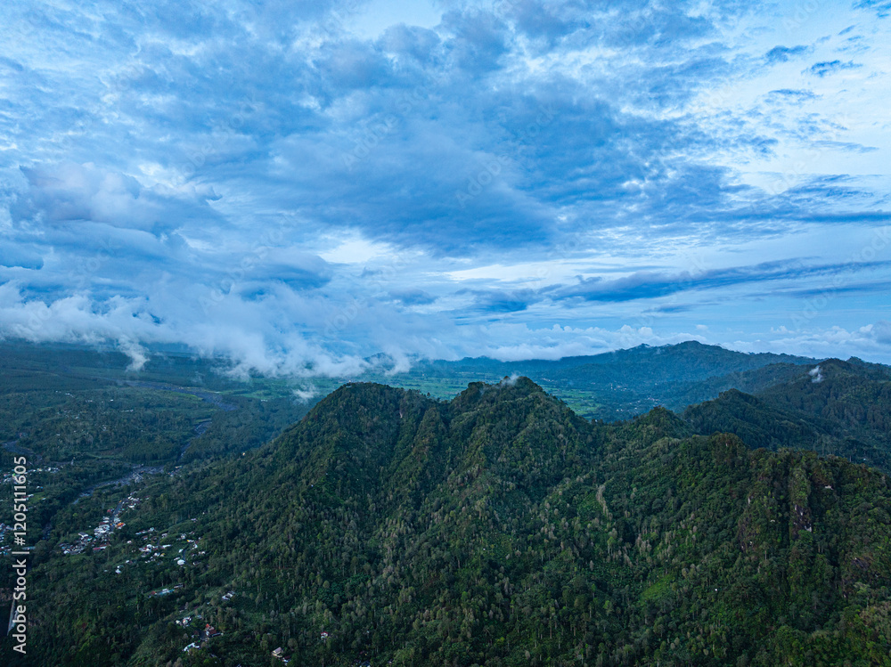 Aerial view Kabut Pelangi Waterfall in East Java. The waterfall stream flows into the mountain gorge in a long path.Above is the residence of the villagers. Abundance of forests on the green mountain. Aerial view Kabut Pelangi Waterfall in East Java. The waterfall stream flows into the mountain gorge in a long path.Above is the residence of the villagers. Abundance of forests on the green mountain.