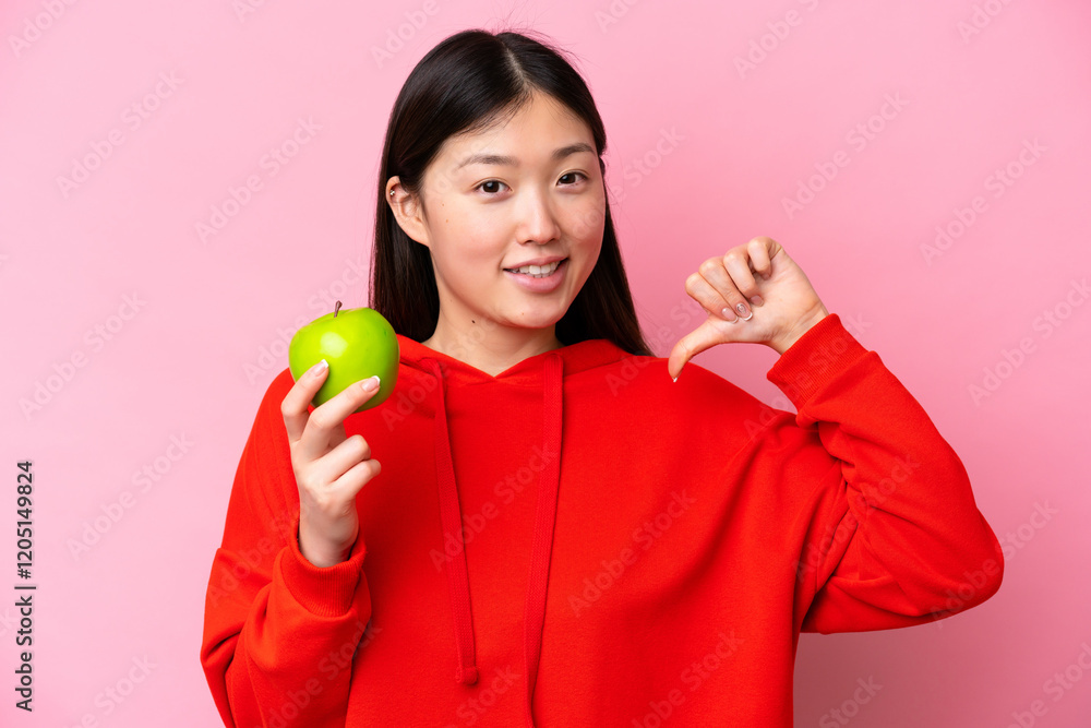 Young Chinese woman with an apple isolated on pink background proud and self-satisfied Young Chinese woman with an apple isolated on pink background proud and self-satisfied