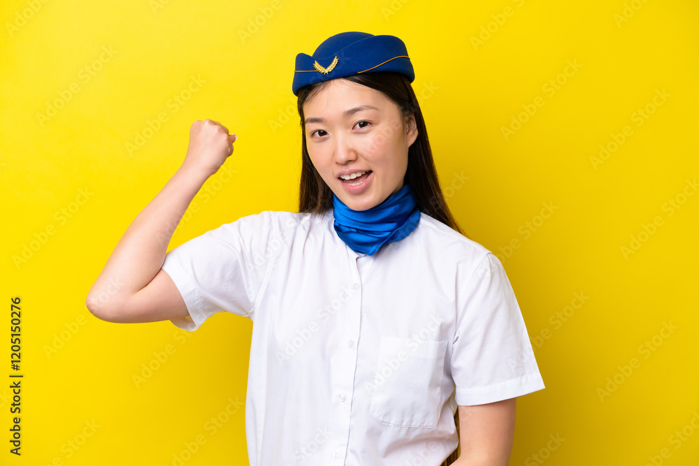 Airplane Chinese woman stewardess isolated on yellow background doing strong gesture Airplane Chinese woman stewardess isolated on yellow background doing strong gesture