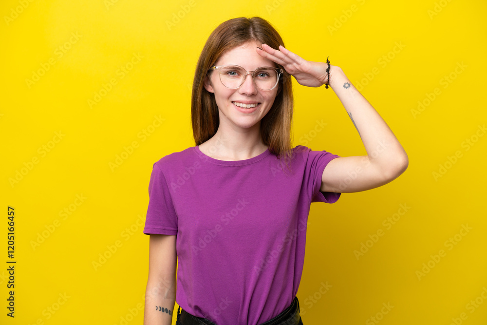Young English woman isolated on yellow background saluting with hand with happy expression Young English woman isolated on yellow background saluting with hand with happy expression