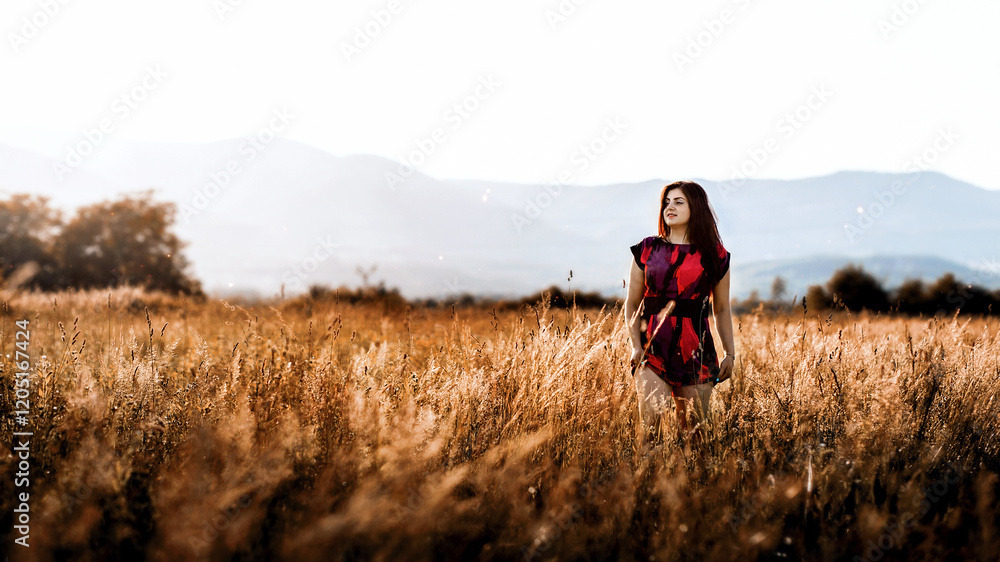girl standing in a field with tall grass. She is wearing a short dress with a bright pattern, which is dominated by red and black colors. girl standing in a field with tall grass. She is wearing a short dress with a bright pattern, which is dominated by red and black colors.