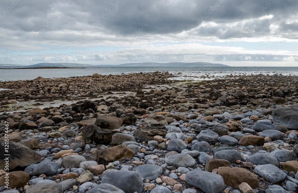 Rocky shoreline at Silverstrand Beach, Galway, Ireland, with calm sea and cloudy sky Rocky shoreline at Silverstrand Beach, Galway, Ireland, with calm sea and cloudy sky