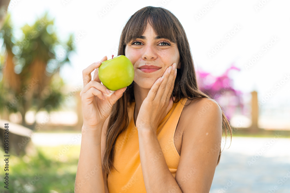 Young woman at outdoors holding an apple Young woman at outdoors holding an apple