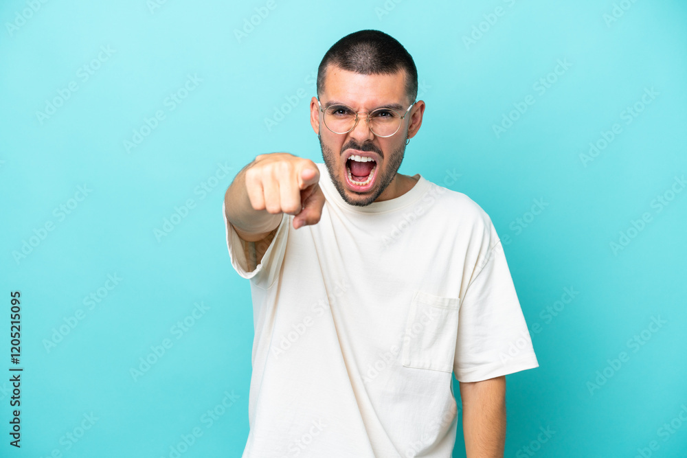 Young caucasian man isolated on blue background frustrated and pointing to the front Young caucasian man isolated on blue background frustrated and pointing to the front